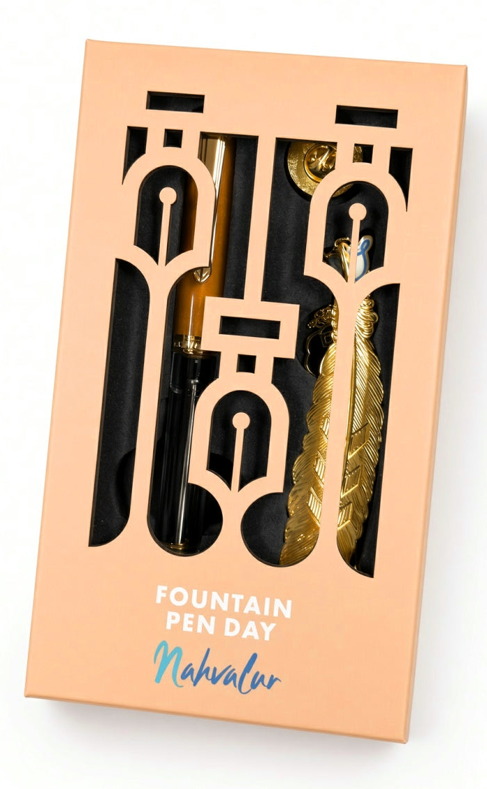 A Nahvalur Original Plus Fountain Pen - Fountain Pen Day 2026 (Limited Edition) and a metallic feather-shaped bookmark inside a peach-colored box with cutouts and the text Fountain Pen Day.