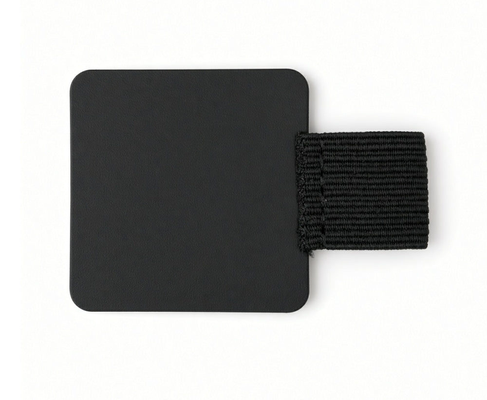 The FPR Pen Loop – self-adhesive pen notebook holder features a black square patch with rounded corners and an attached horizontal black elastic band, creating a sleek and practical journal accessory perfect for securely holding your pen on a white background.