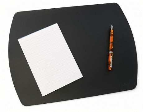 A black Girologio Writing Mat - Black with rounded corners, featuring a lined notepad and an orange marbled fountain pen, providing stylish desk protection.
