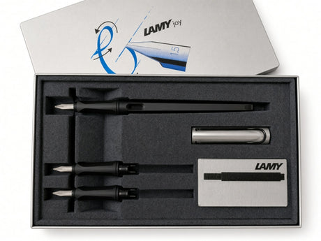 Discover the art of beautiful writing with the LAMY Joy Calligraphy Set - AL Black. This premium set features a sleek black calligraphy fountain pen, three interchangeable calligraphy nibs for versatile lettering styles, a sophisticated silver pen case, ink cartridges, and a LAMY-branded box—all neatly organized in a foam insert for convenient storage and elegant presentation.