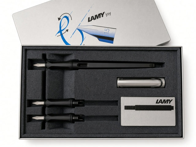 Discover the art of beautiful writing with the LAMY Joy Calligraphy Set - AL Black. This premium set features a sleek black calligraphy fountain pen, three interchangeable calligraphy nibs for versatile lettering styles, a sophisticated silver pen case, ink cartridges, and a LAMY-branded box—all neatly organized in a foam insert for convenient storage and elegant presentation.