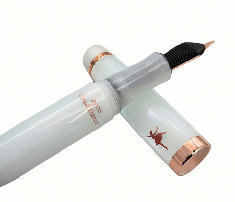 Translucent white Opus 88 Harmony fountain pen with copper-colored accents, featuring a silhouette of a dancer and the text 2026 Cloud Dancer on the barrel.