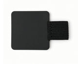 The FPR Pen Loop – self-adhesive pen notebook holder features a black square patch with rounded corners and an attached horizontal black elastic band, creating a sleek and practical journal accessory perfect for securely holding your pen on a white background.