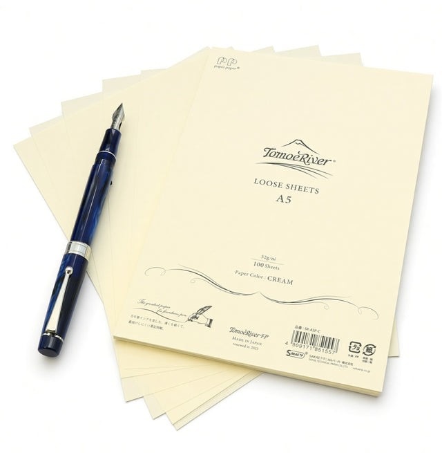 A stack of cream-colored Tomoe River A5 Loose-leaf Sheets (52gsm) with a blue fountain pen resting on top.